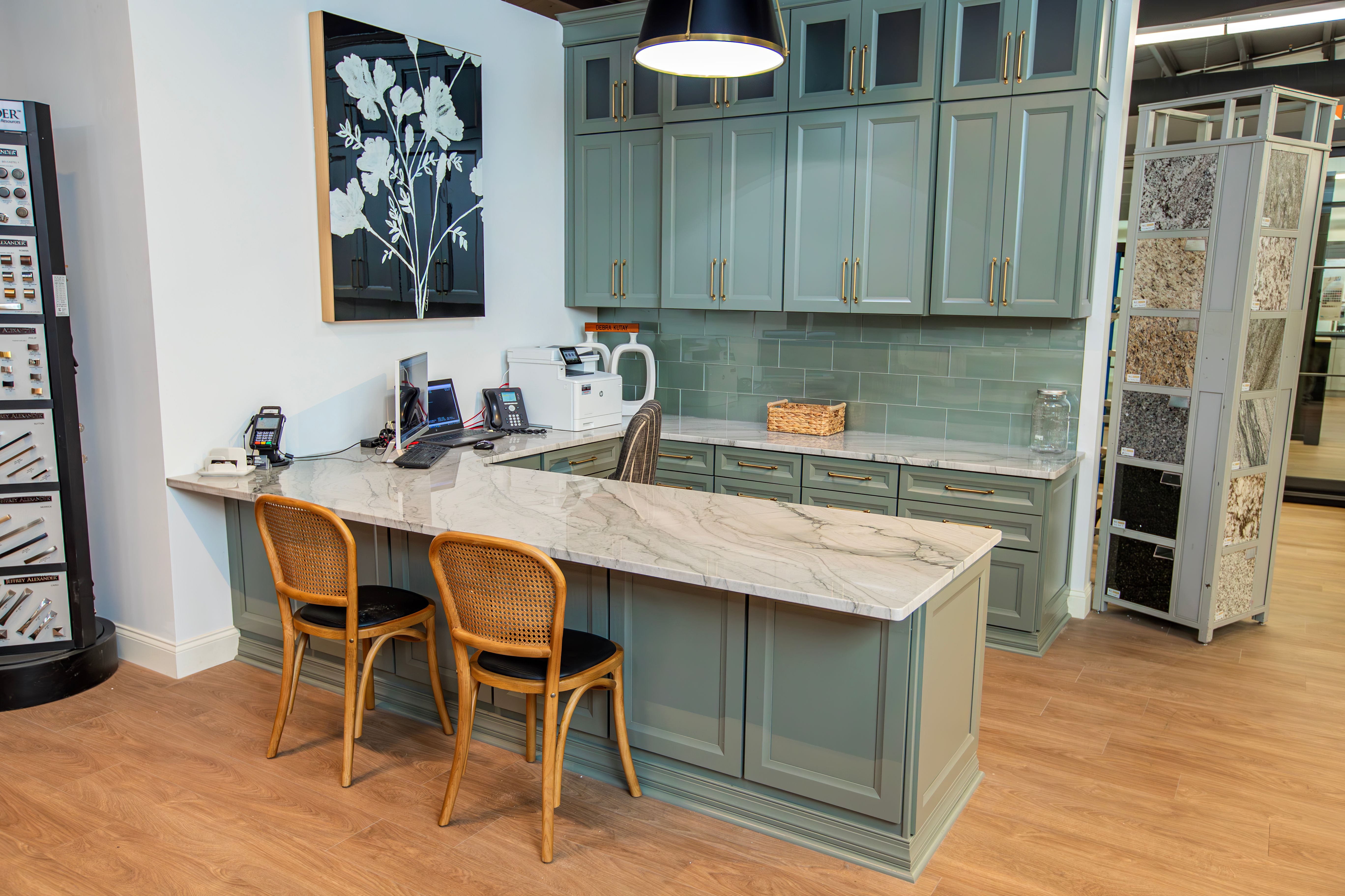 Kitchen display with green upper and lower cabinets and marble countertops